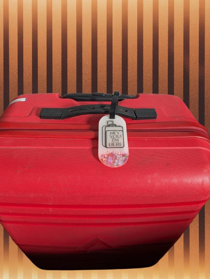 Red suitcase with a tag on a wooden floor