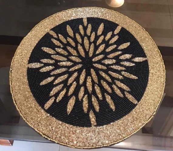 Round woven mat with black center and gold border on a reflective surface