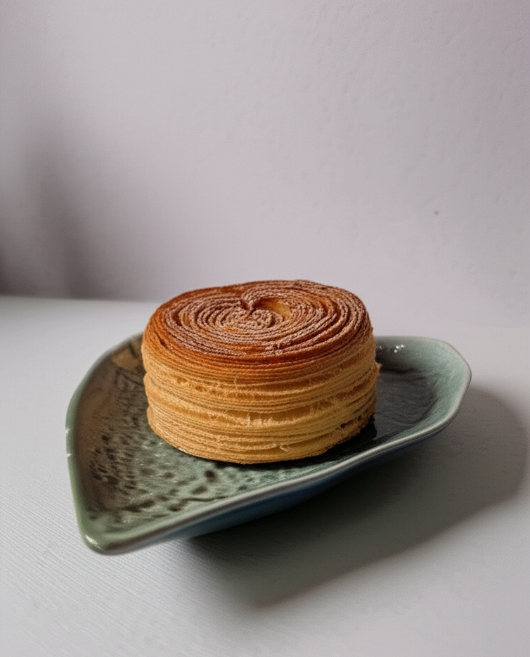 Stack of layered cookies on a green ceramic plate with a plain background