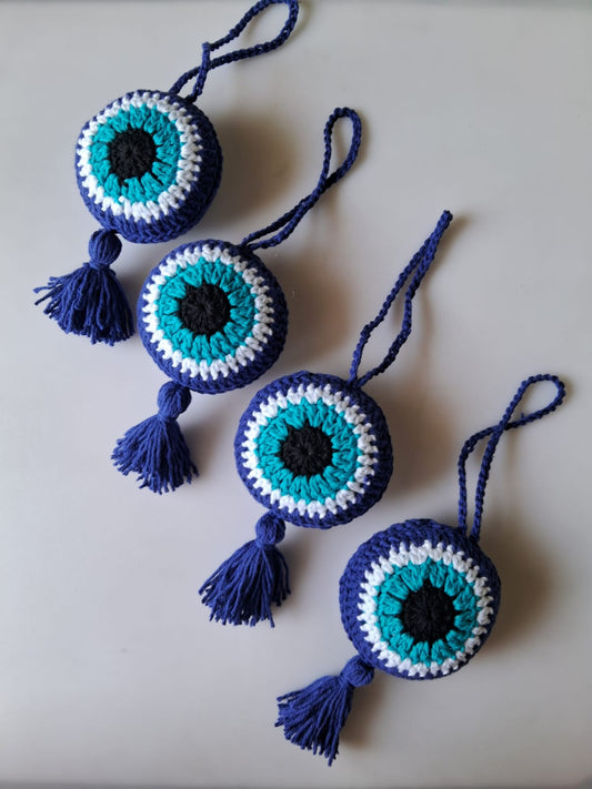 Crocheted eye-shaped decorations with tassels on a light background
