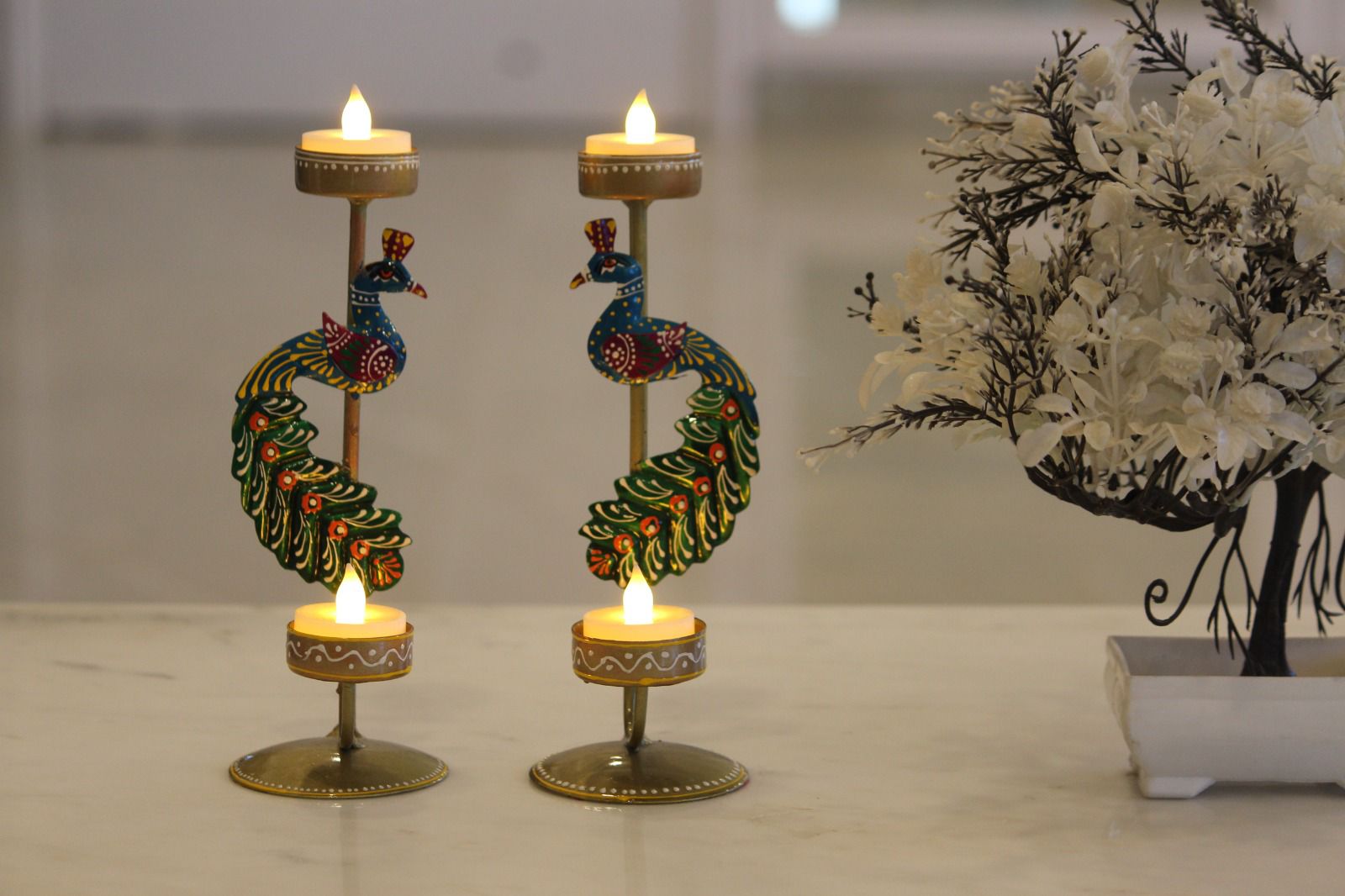 Decorative candle holders with candles on a reflective surface.