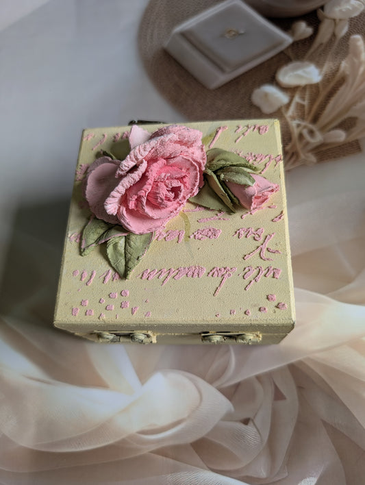Decorative box with pink roses and intricate designs on a soft fabric background