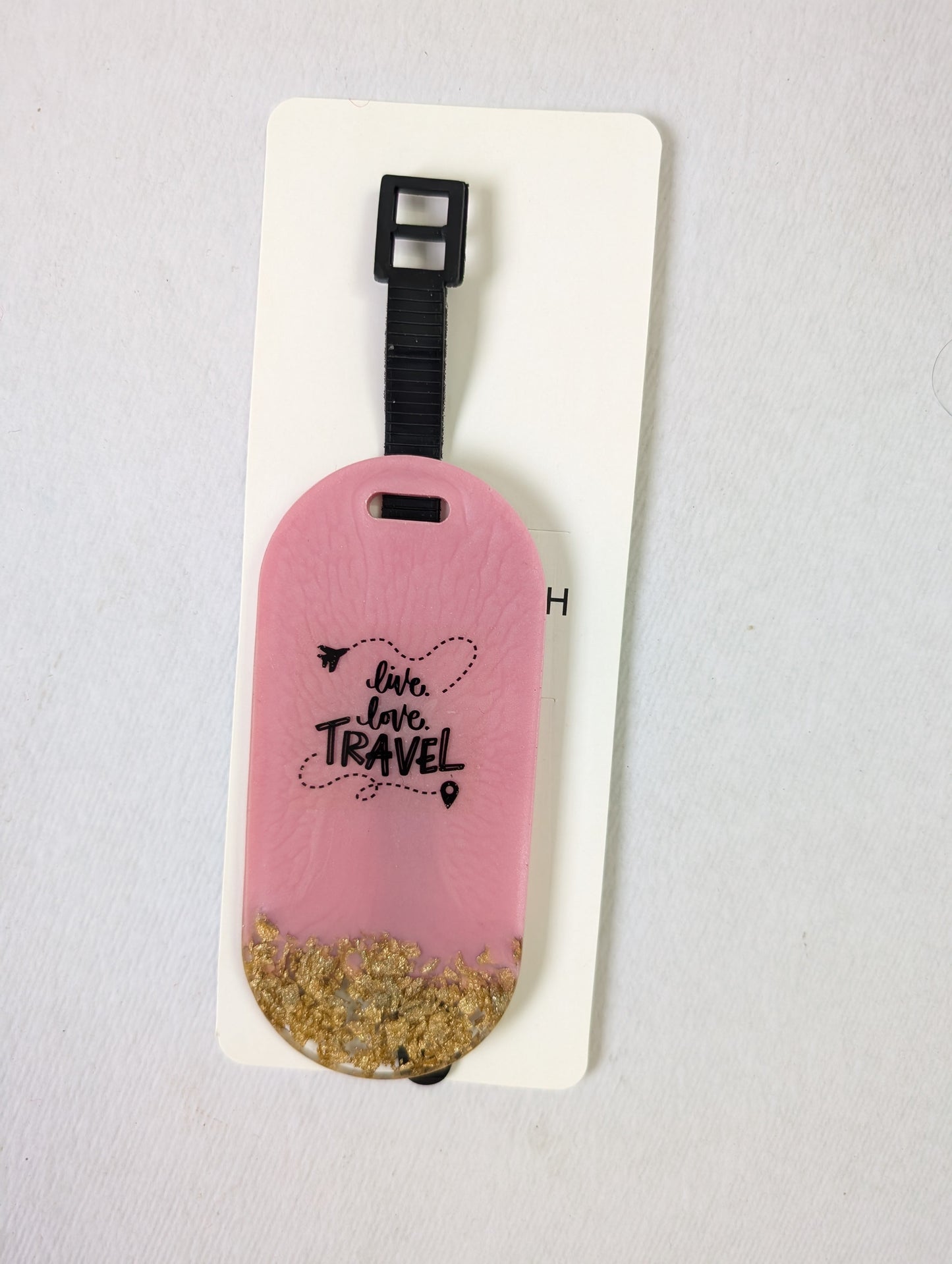 Pink luggage tag with glittery gold accent and text on a white background