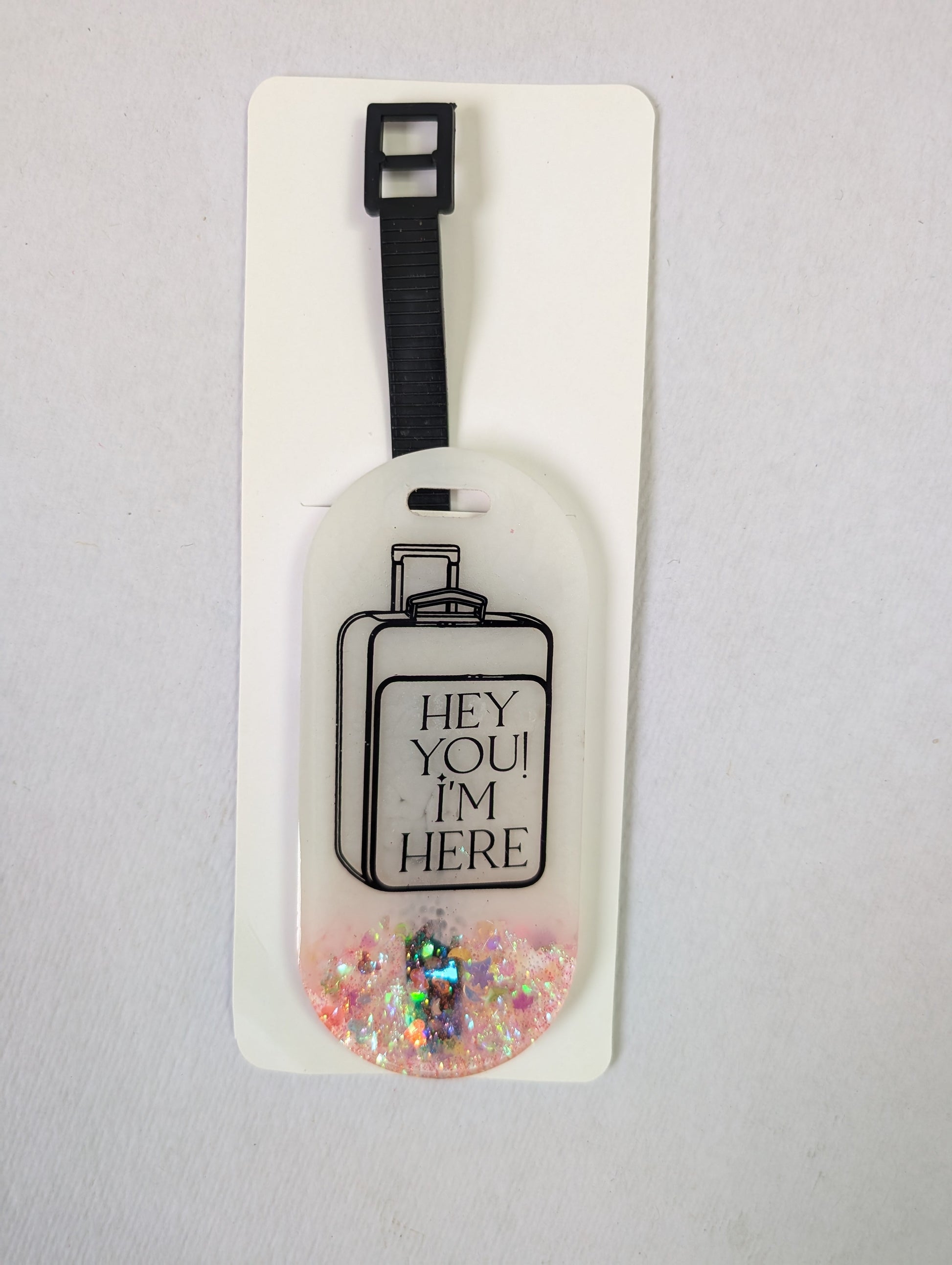 Luggage tag with decorative glittery design on a plain background