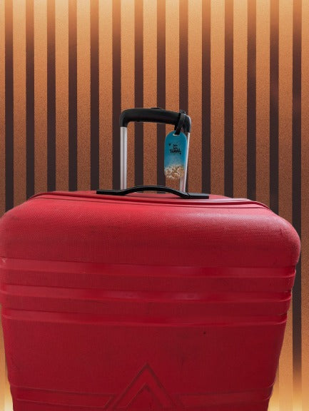 Red suitcase with a blue tag against a striped wall