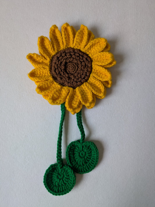 Crocheted sunflower with green stem curtain tie-up on a plain background