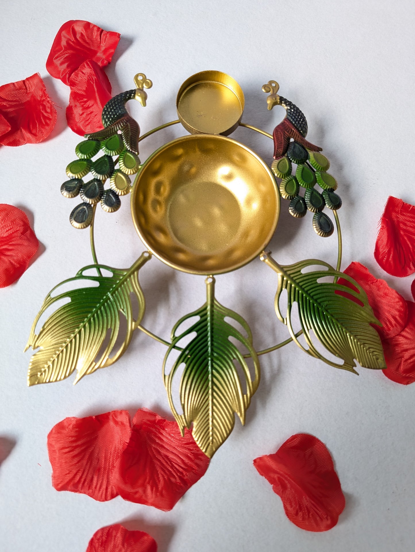 Decorative gold bowl with green leaves and red flowers on a white background