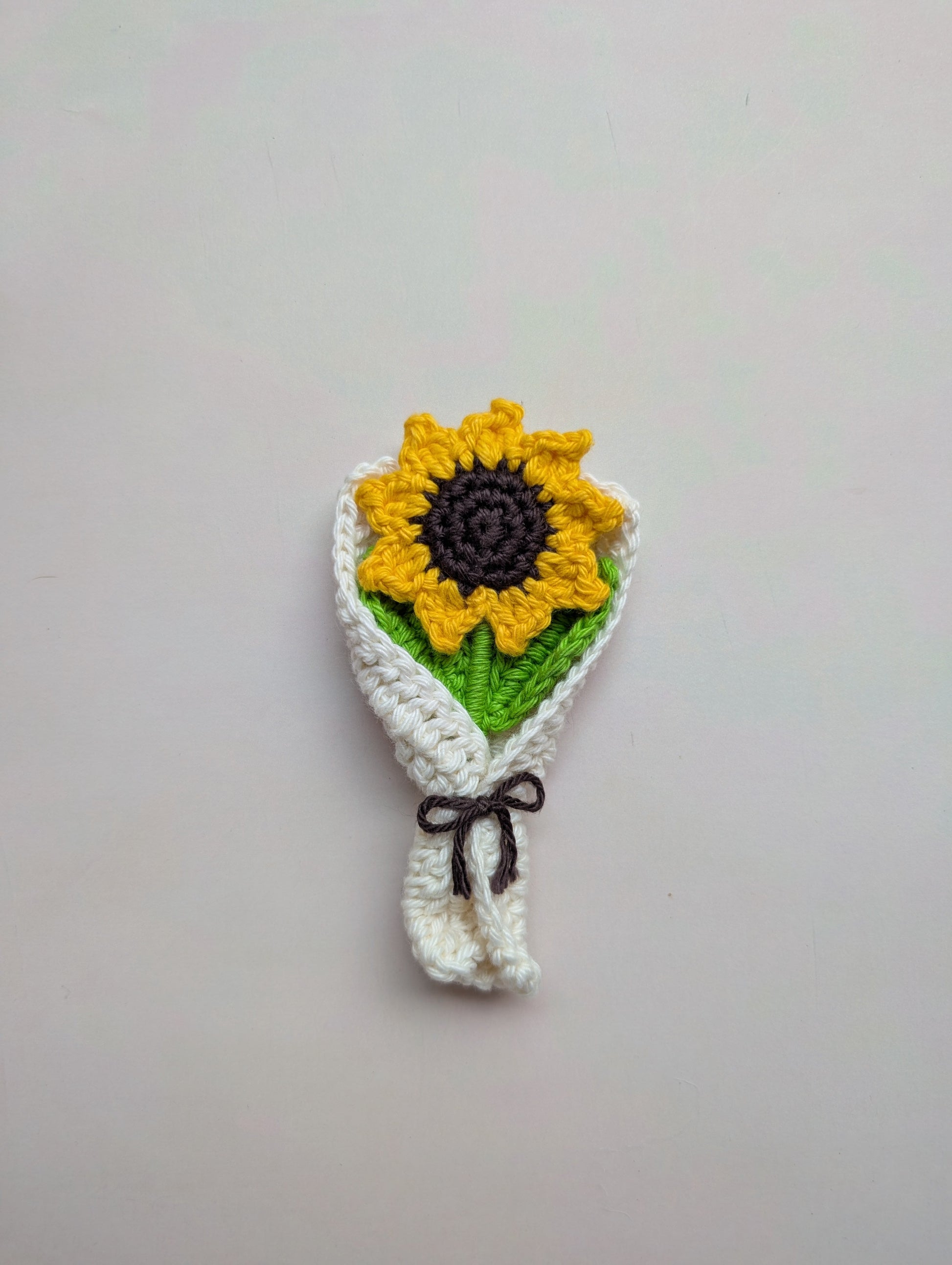 Crocheted sunflower headband on a plain background