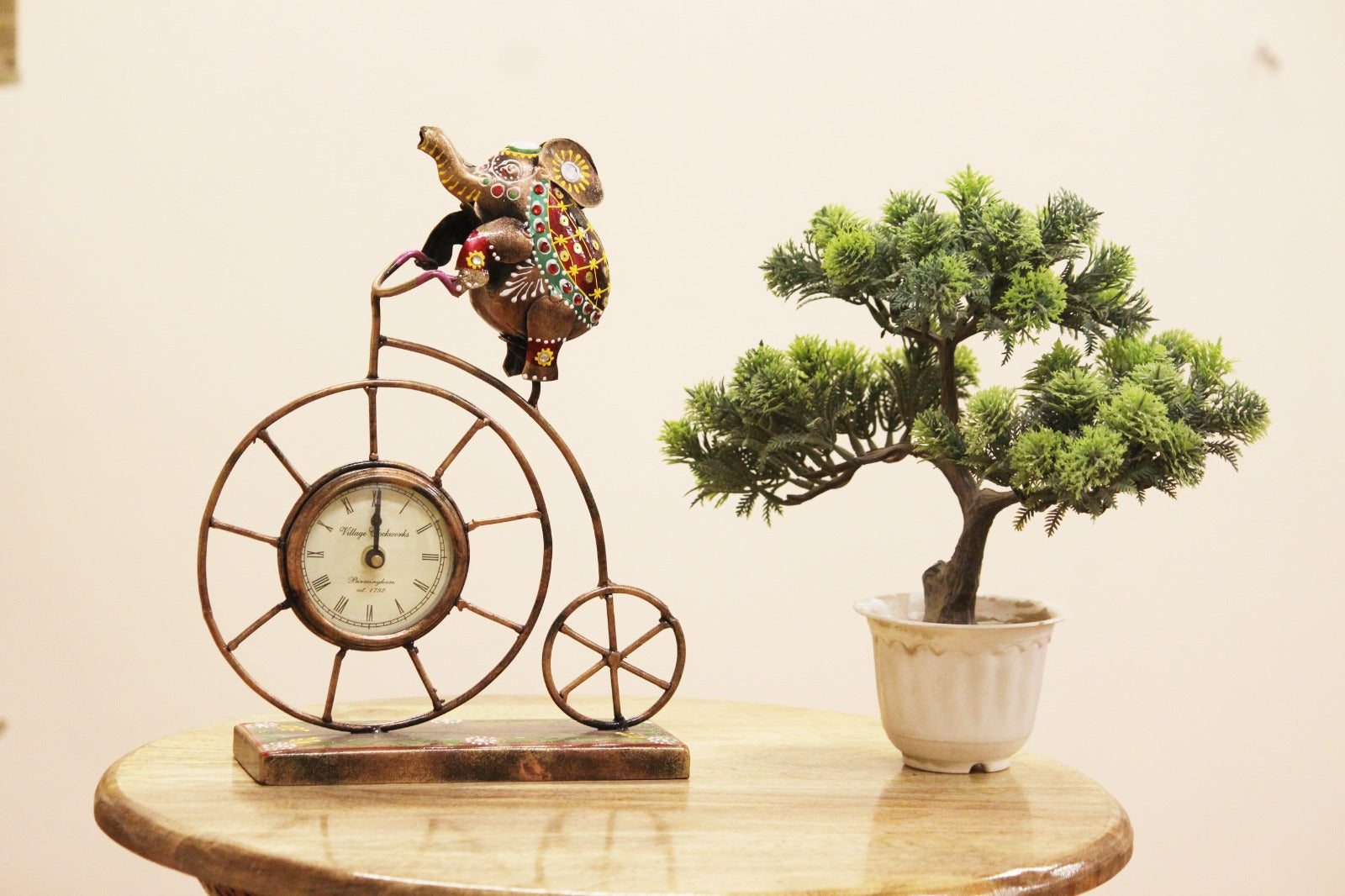 Decorative clock on a bicycle frame with a small potted plant on a wooden surface.