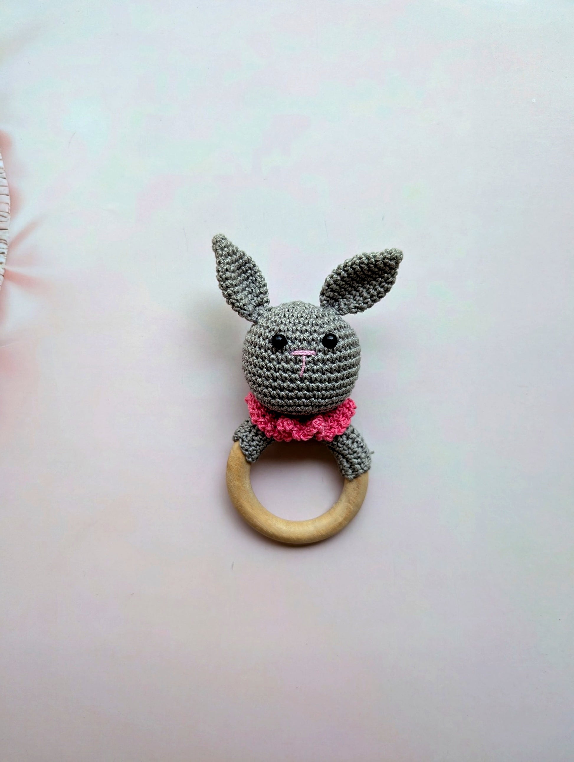 Crocheted animal teether with a wooden ring on a light background